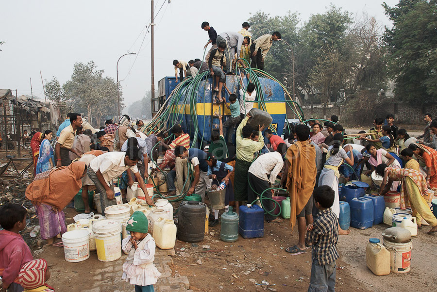 Die Bewohner des Slumsviertels bringen Kanister, Eimer und Schläuche um Wasser zu holen.